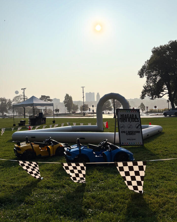 Large outdoor setup featuring bumper cars and mini Lambo at a public park.